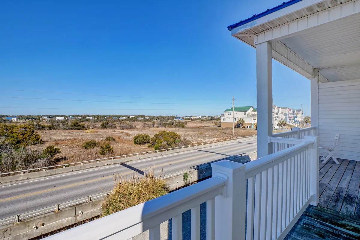 A peaceful view of an open landscape with a roadway leading toward distant houses, surrounded by coastal greenery. The perspective captures the sense of journey and exploration that comes with traveling the coastal Carolina area, and the visible roadway hints at the ease of setting off for local attractions.