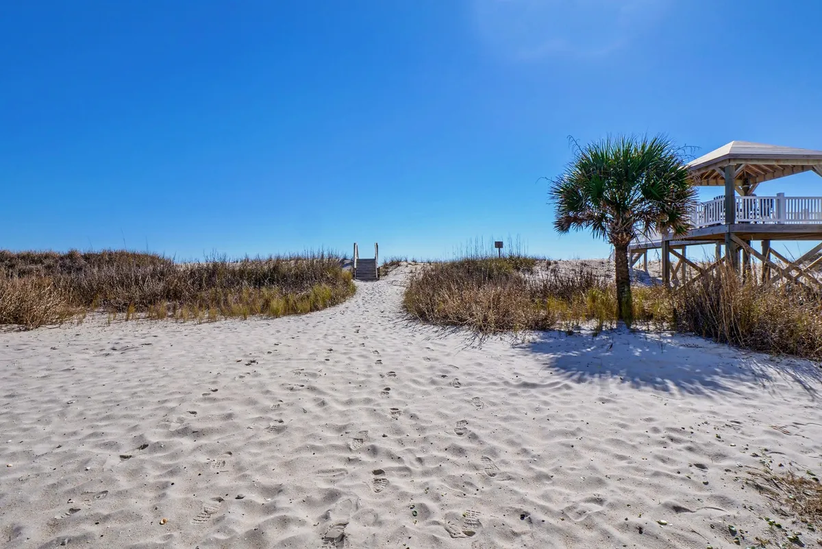 A charming exterior with a palm tree–lined pathway leading to the beach, complete with a gazebo nearby. The inviting walkway hints at local adventures, picnics, and easy access to fresh air and seaside dining.